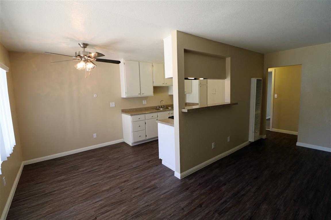 A kitchen area with a fan and wooden flooring.